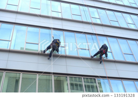 Workers cleaning windows in a high-rise building 133191328