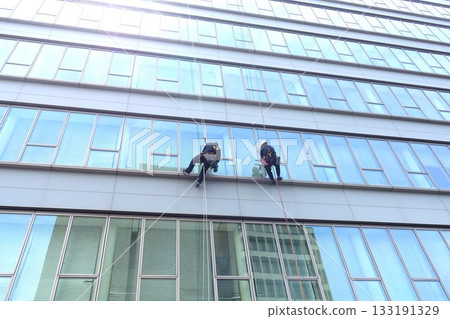 Workers cleaning windows in a high-rise building 133191329