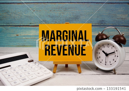 Marginal Revenue text written on paper card with calculator and alarm clock on wooden background 133191541