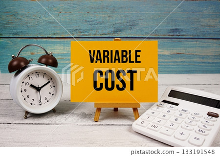 Variable Cost text written on paper card with calculator and alarm clock on wooden background Variable Cost text written on paper card with calculator and alarm clock on wooden background 133191548