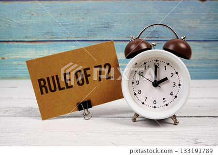 Rule Of 72 text written on paper card with alarm clock on wooden background Rule Of 72 text written on paper card with alarm clock on wooden background 133191789