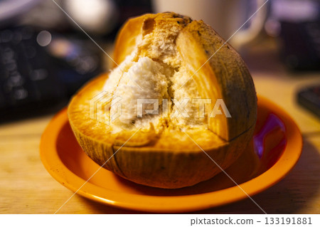 Sliced Santol Reveals Inside On Table, A vibrant ad photo of sliced santol exposing juicy flesh on a rustic table, seeds glistening under warm light, perfect for tropical fruit or harvest showcase. 133191881