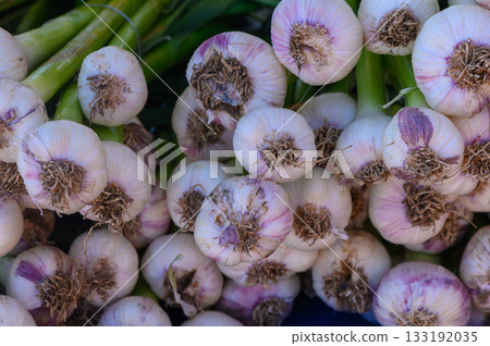 Freshly harvested garlic bulbs arranged in vibrant display at a local farmers market in the heart of summer 133192035