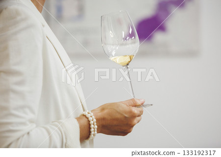 Female hand holding white wine glass and tasting it on blurred wine region map background. Female hand holding white wine glass and tasting it on blurred wine region map background. 133192317
