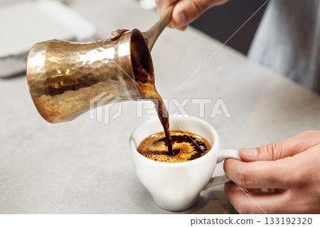 Traditional Turkish Coffee Being Poured From Copper Cezve Into White Cup Traditional Turkish Coffee Being Poured From Copper Cezve Into White Cup 133192320