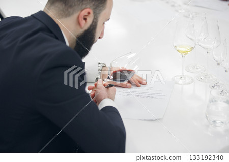 Sommelier analysing color of the red wine during the tasting. Training of wine masters, certification, wine school. Sommelier analysing color of the red wine during the tasting. Training of wine masters, certification, wine school. 133192340