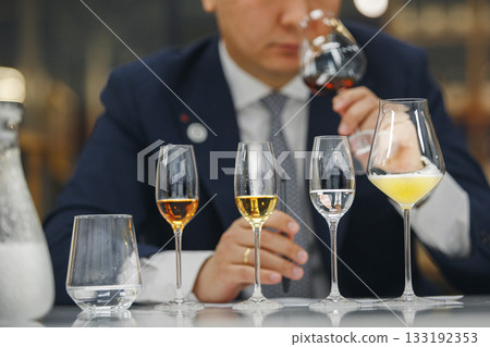 Beginner wine waiter sniffs alcoholic drink during blind tasting. Sommelier school, international certification. 133192353