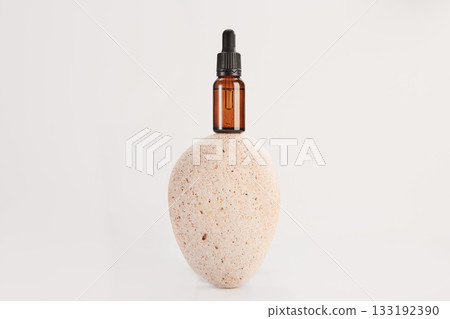Glass amber vial on spa stone on cream background. 133192390