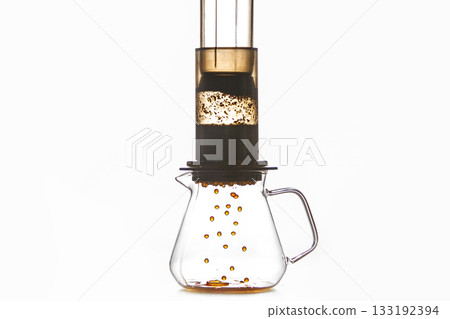 Brewing of Coffee by Creates Pressure Aeropress Method Where Drops Flow From Flask Into Glass Pot, Creating Rich and Fragrant Coffee Drink Against White Background with a Free Copy Space Brewing of Coffee by Creates Pressure Aeropress Method Where Drops Flow From Flask Into Glass Pot, Creating Rich and Fragrant Coffee Drink Against White Background with a Free Copy Space 133192394