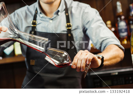 Sommelier pouring wine into glass from mixing bowl. Male waiter 133192418