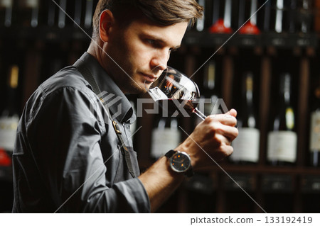 Bokal of red wine on background, male sommelier appreciating drink 133192419