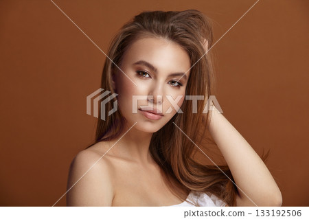 Attractive lady with loose hair posing for camera on brown Attractive lady with loose hair posing for camera on brown 133192506