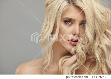 Beauty portrait of caucasian woman with blonde curly hair on beige isolated 133192520