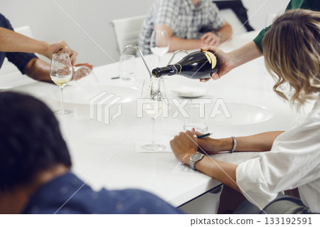 Bartender pours sparkling wine into glasses for the participants of the training held at the sommelier training school. Bartender pours sparkling wine into glasses for the participants of the training held at the sommelier training school. 133192591