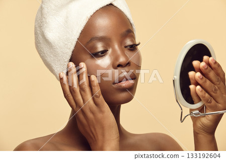 Pretty Afro-american woman applying under eyes mask. Pretty Afro-american woman applying under eyes mask. 133192604
