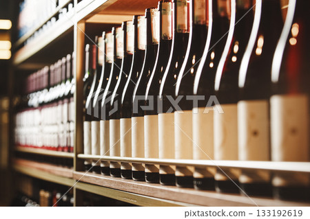 Bottles of still wine on the shelf, close-up image of alcoholic beverages in the wine cellar. 133192619