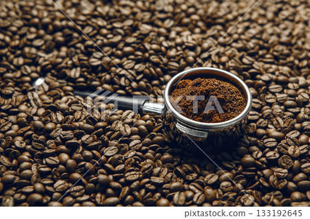 Freshly Ground Coffee in Portafilter on Roasted Coffee Beans Close Up Freshly Ground Coffee in Portafilter on Roasted Coffee Beans Close Up 133192645