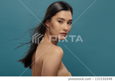 Well-groomed asian girl looking over shoulder to camera. Well-groomed asian girl looking over shoulder to camera. 133192646