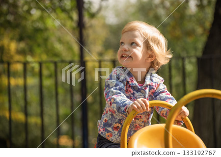 A little girl is sitting on a yellow swing A little girl is sitting on a yellow swing 133192767