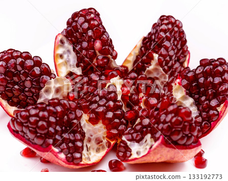 A close up of a pomegranate fruit with a few pieces missing A close up of a pomegranate fruit with a few pieces missing 133192773