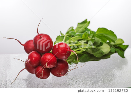 A bunch of radishes are displayed on a wet table A bunch of radishes are displayed on a wet table 133192780