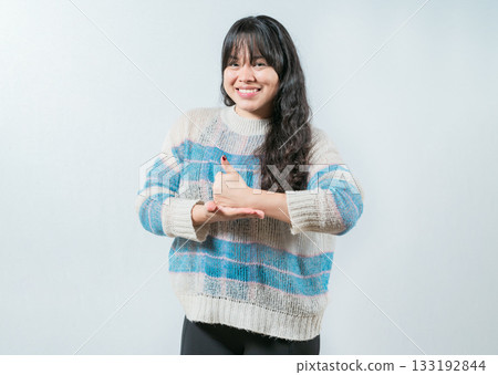 Asian girl gesturing help with hands in nonverbal language. Smiling woman showing help gesture with hands in sign language Asian girl gesturing help with hands in nonverbal language. Smiling woman showing help gesture with hands in sign language 133192844