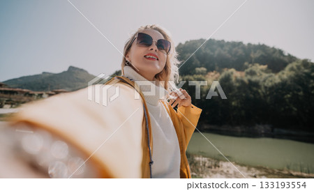 Woman in Yellow Jacket Taking a Selfie by a Lake 133193554
