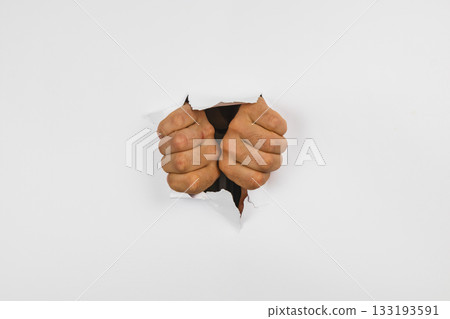 Fists breaking through a white wall create a striking visual impact 133193591