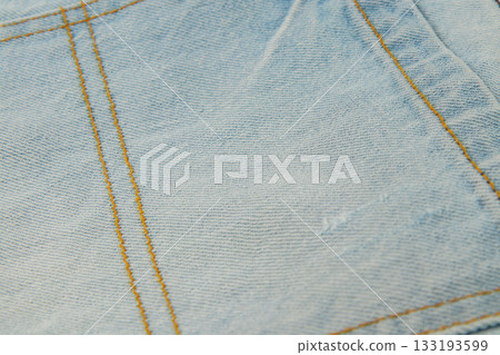 Denim fabric close-up showing blue color and yellow stitching details Denim fabric close-up showing blue color and yellow stitching details 133193599
