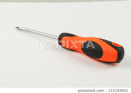 Screwdriver with an orange and black handle on a white surface 133193602