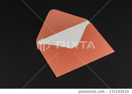 Orange envelope with a white insert lying on a black background 133193610