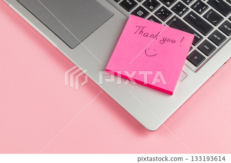 Thank you note on pink sticky pad next to laptop on a pink background Thank you note on pink sticky pad next to laptop on a pink background 133193614