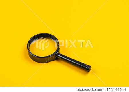 Simple black magnifying glass against a bright yellow background Simple black magnifying glass against a bright yellow background 133193644