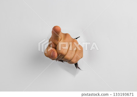 Hand pointing through a hole in white wall creating a striking visual effect Hand pointing through a hole in white wall creating a striking visual effect 133193671