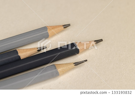 a row of black pencils folded on cheap loose paper, wooden pencils with graphite lead for drawing or other work a row of black pencils folded on cheap loose paper, wooden pencils with graphite lead for drawing or other work 133193832
