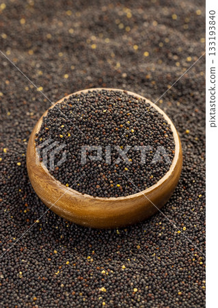 a large number of black rapeseed seeds are used to produce rapeseed oil, black rapeseed is used to produce food products, round wooden bowl filled with round rapeseed 133193840