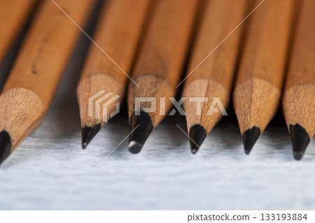 wooden pencils with black lead on blue corrugated paper, several monochrome pencils for sketches or graphic work wooden pencils with black lead on blue corrugated paper, several monochrome pencils for sketches or graphic work 133193884