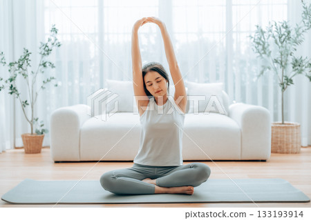Happy young Asian woman practicing yoga and shoulder stretching at home Happy young Asian woman practicing yoga and shoulder stretching at home 133193914