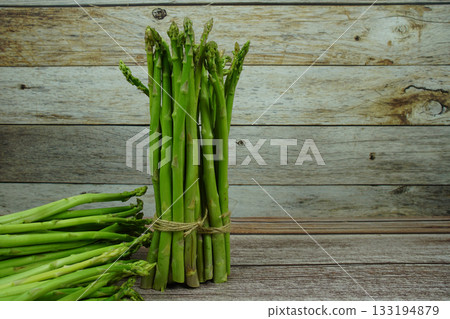 Bunch of fresh green asparagus stems on wooden background Bunch of fresh green asparagus stems on wooden background 133194879