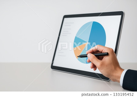 Businessman analyzing pie chart on tablet with stylus in office setting Businessman analyzing pie chart on tablet with stylus in office setting 133195452