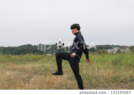 Side shot of a man practicing football juggling 133195667
