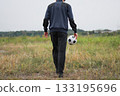 Rear view of a man kicking a soccer ball 133195696