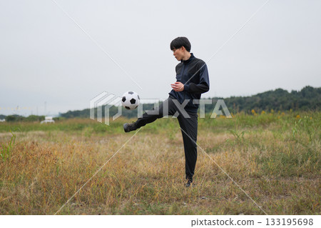 A man practicing soccer juggling 133195698