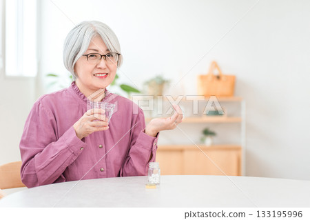 Gray-haired senior woman holding medicine, supplements, and oral medication 133195996