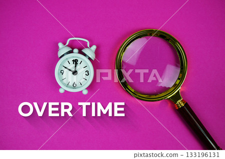 Alarm clock and a magnifying glass on a bright pink background, with text "Over Time" 133196131