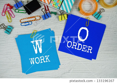 WO - Work Order text on stick note with stationery on concrete background 133196167