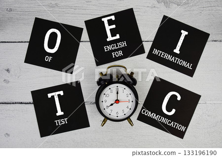 TOEIC Test of English for International Communication with alarm clock on wooden background 133196190