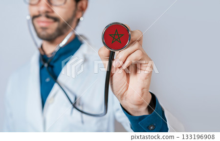 Doctor holding stethoscope with Morocco flag. Morocco health and care concept. Morocco flag on stethoscope Doctor holding stethoscope with Morocco flag. Morocco health and care concept. Morocco flag on stethoscope 133196908