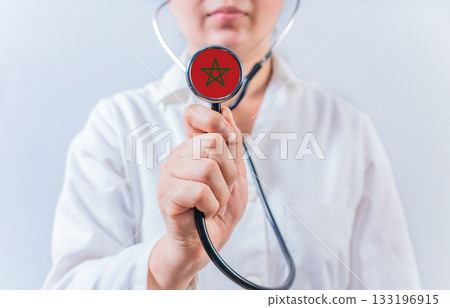 Female doctor holding stethoscope with Morocco flag. National health system of Morocco Female doctor holding stethoscope with Morocco flag. National health system of Morocco 133196915