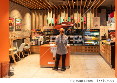 Worker standing at a counter in a modern donut shop with colorful decor in Seoul, South Korea 133197095